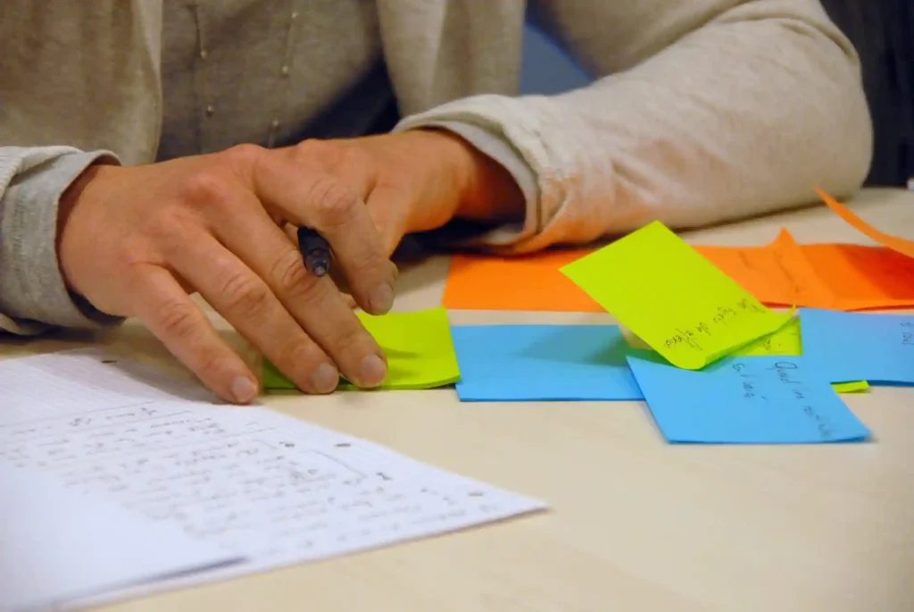 Close-up of a person brainstorming with colorful sticky notes and handwritten notes, planning an AI-related project or concept.