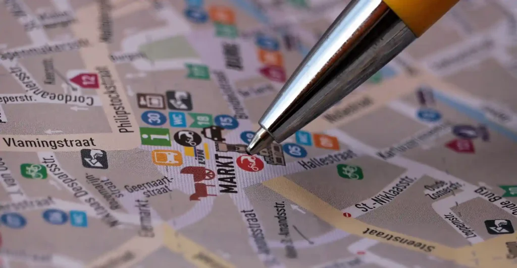 Close-up of a detailed city map with a pen pointing to a specific location, illustrating the use of GIS in architecture for urban planning and spatial analysis.