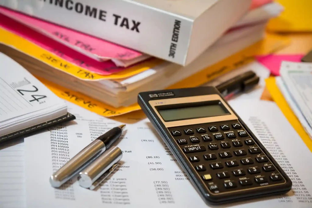 Calculator, pens, and tax documents scattered on a table, symbolizing the financial and initial preparatory work phase in architecture projects.