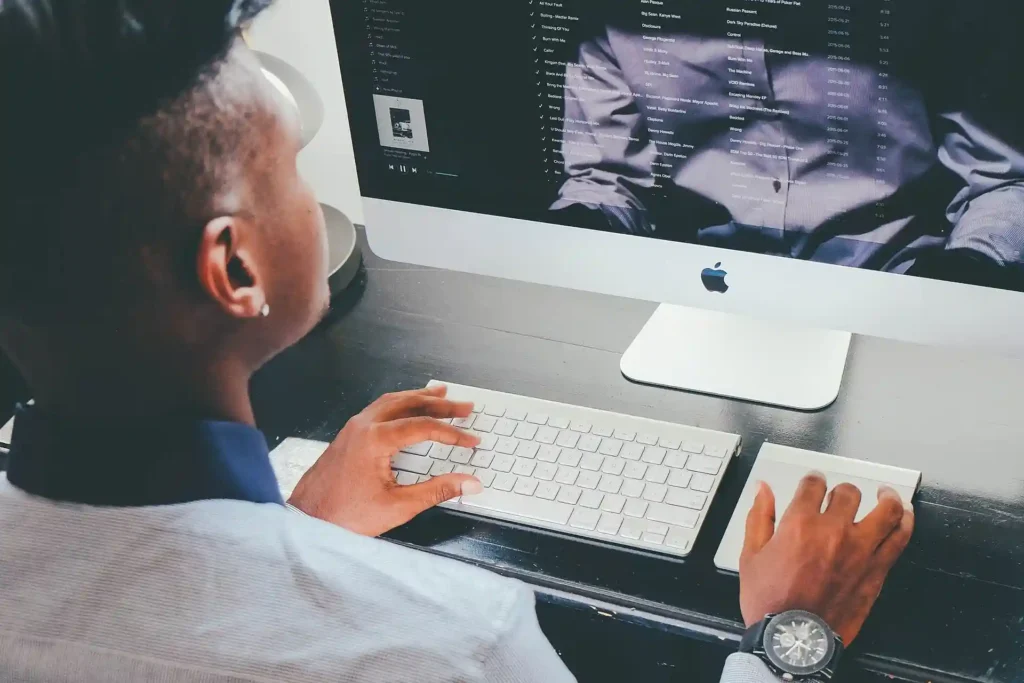 Person working on an Apple desktop computer, highlighting a user-friendly interface for easy navigation and efficient workflow.